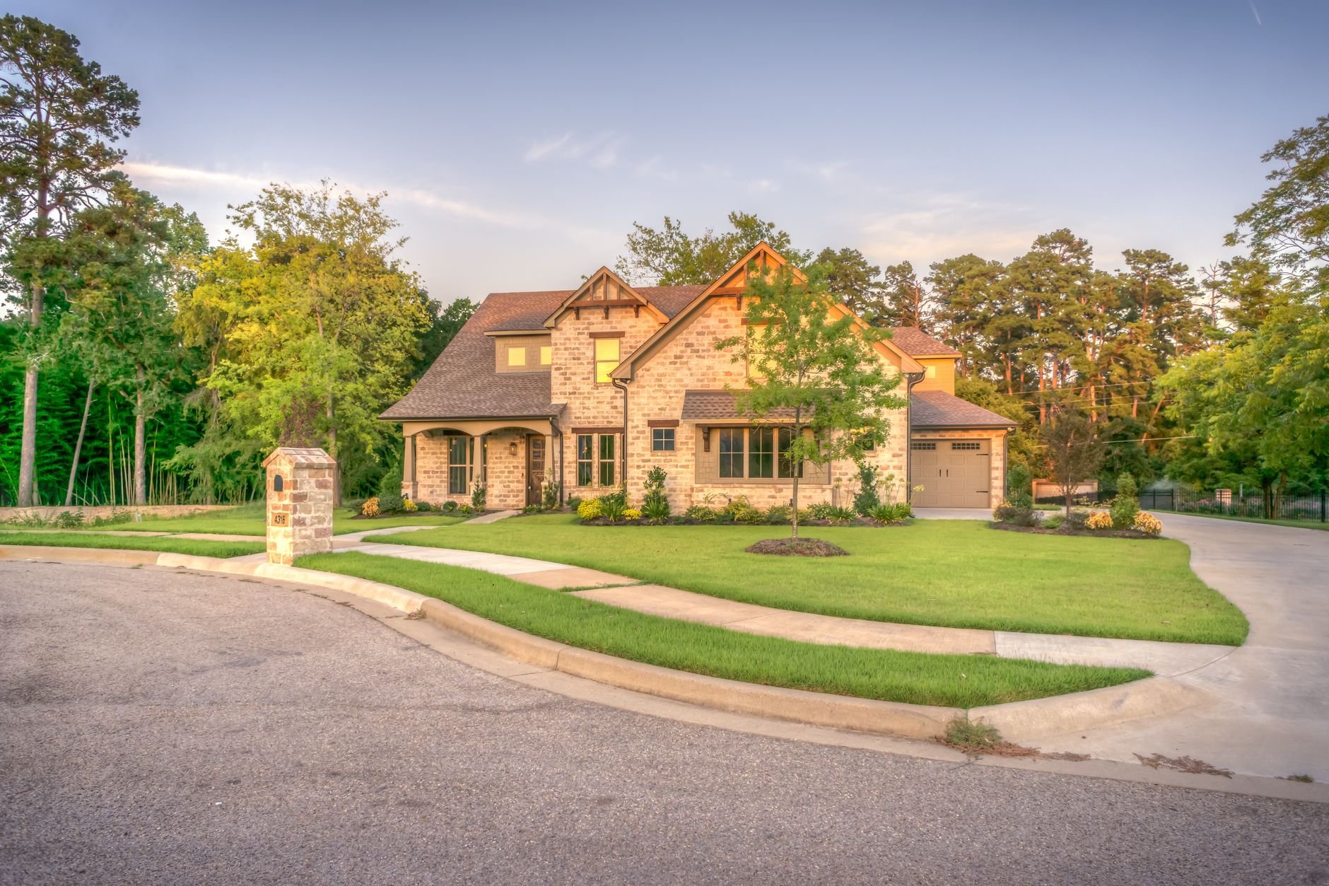 Elegant stone family home with manicured lawn and driveway