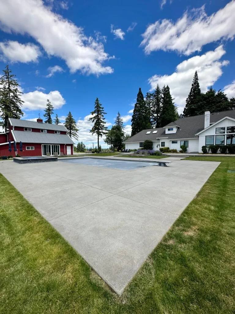 Pristine pool deck and estate property with lounge chairs, red barn, and Pacific Northwest trees after Tend cleaning