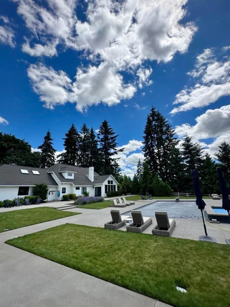 Clean pool deck with lounge chairs, swimming pool, and tall Pacific Northwest trees at a high-end property